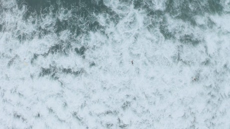 Aerial view of the sea and people surfing.