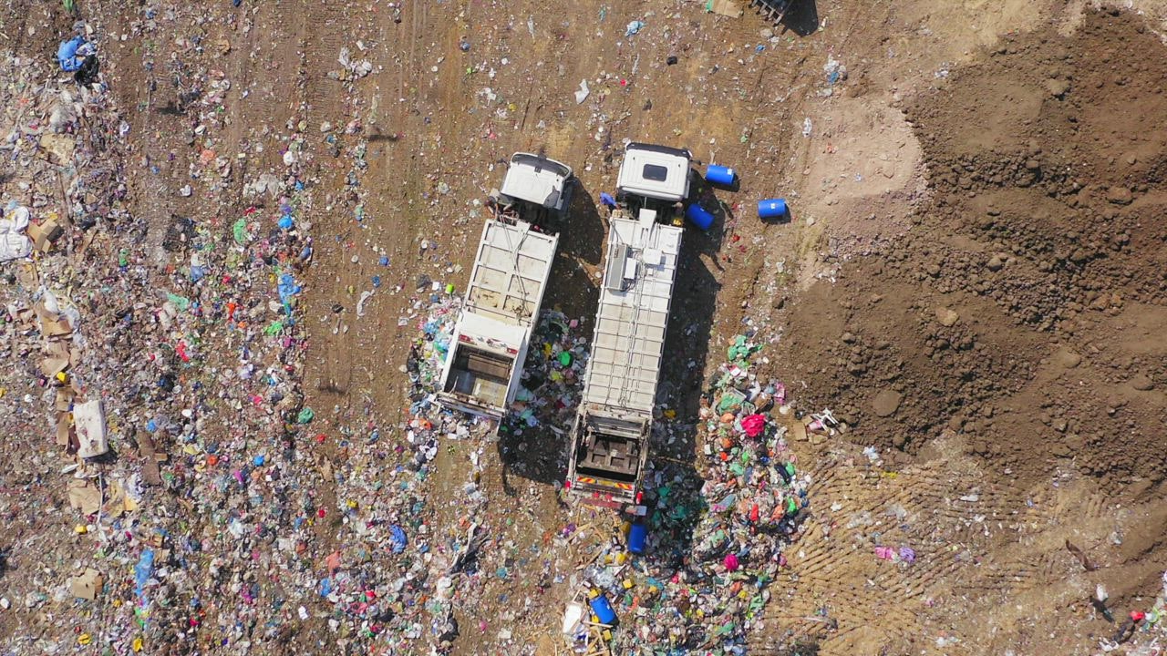 ⁣Aerial view of  ayo judi trucks emptying rubbish into landfill