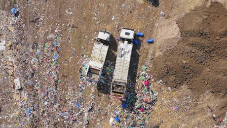 Aerial view of trucks emptying rubbish into landfill.