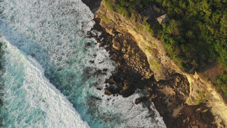 Aerial view of waves breaking on cliffs.