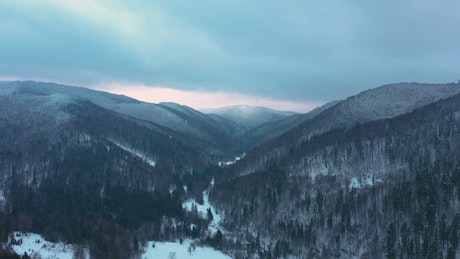 Aerial view of winter forested mountain landscape.