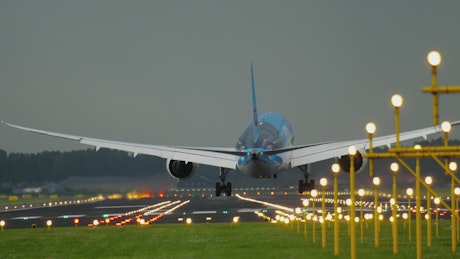 Airplane landing in illuminated airport tracks.