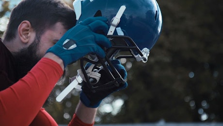American footballer putting a helmet on.