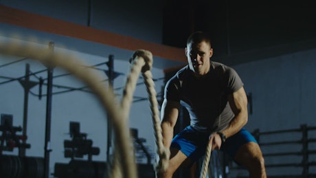 An athlete using thew ropes in the gym.