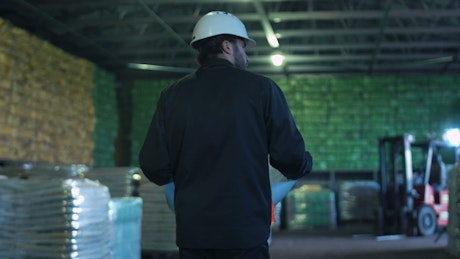 An engineer with blueprint walking on a warehouse