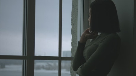 An upset young woman by the window.