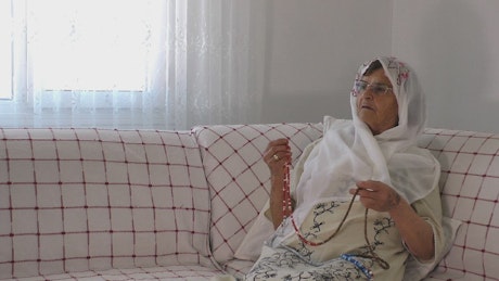 Anciana rezando el Corán con un rosario