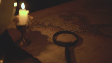 Ancient map of the world in the dark lit by candlelight.