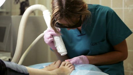Applying laser treatment to feet.