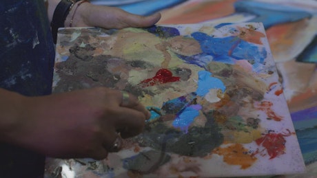 Artist mixing paint on her palette.
