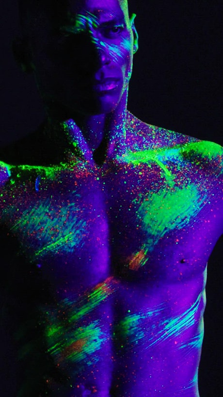 Artistic dance of a man smeared with phosphorescent paint.