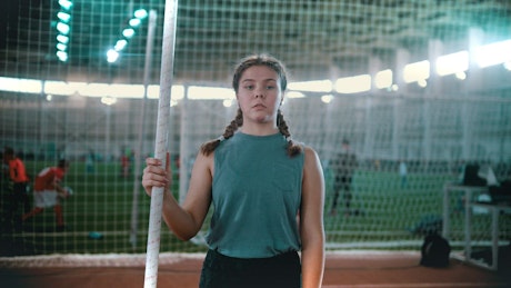 Athlete girl from the front with a pole in her hand.