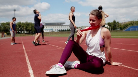 Athlete sitting on a running track holding a medal.