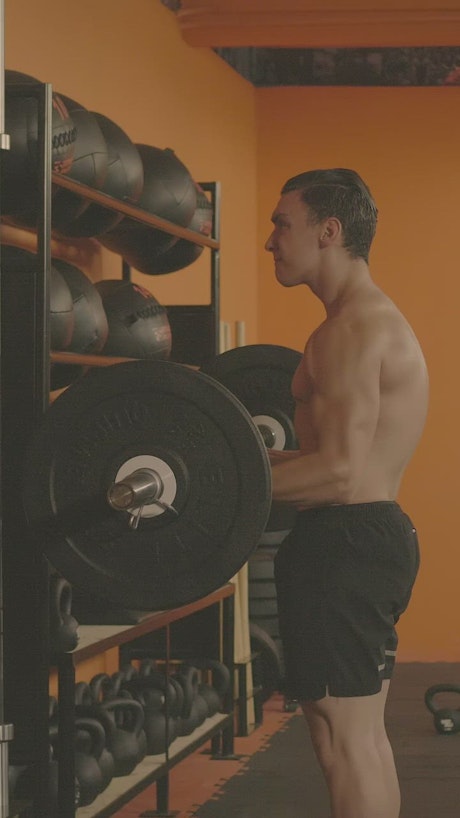Athletic man doing reps with a large dumbbell.