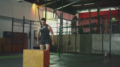 Athletic man jumping a platform in a gym.