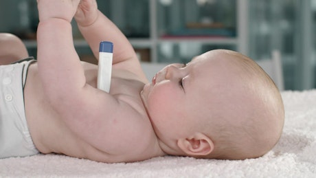 Baby lying with a thermometer in his arm.