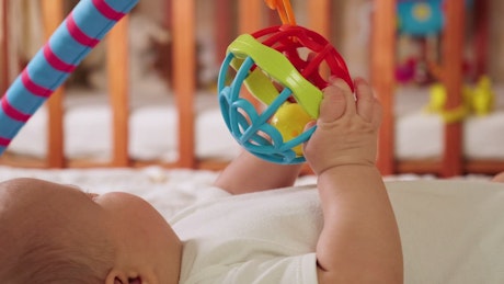 Baby playing with a toy in his crib.