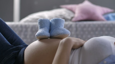 Baby shoes on a woman's pregnant belly.