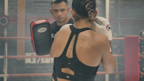 Back view of a woman doing kickboxing with her coach