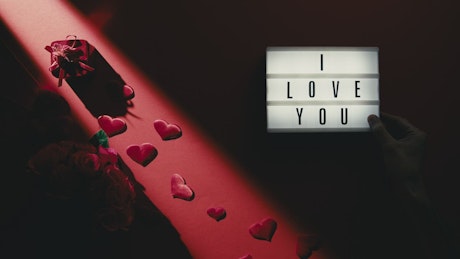 Background of a hand lighting an I love you sign for Valentine's Day.