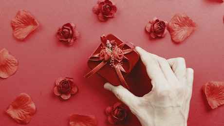 Background of a hand placing a Valentine's Day gift.
