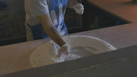 Baker preparing flour for dough or pizza.
