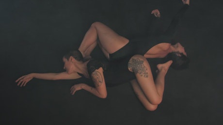 Ballerinas lying on their backs moving their hands gently