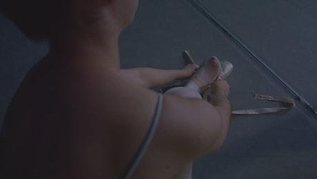Ballet dancer putting on her slippers.
