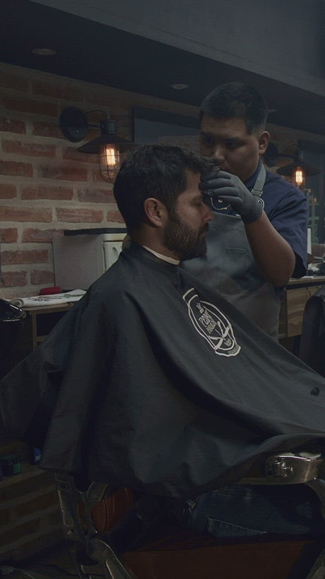 Barber begins to cut the hair of his client.