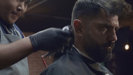 Barber cutting the hair of a bearded man.