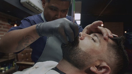 Barber shaping the beard of a man.