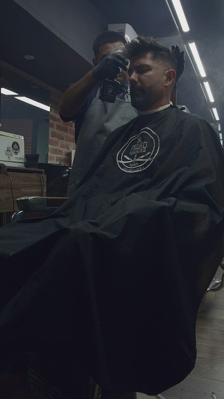 Barber spraying his client's hair.