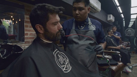 Barber working in his barbershop with a client.