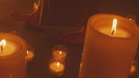 Bare feet of a woman walking among burning candles.