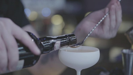 Bartender measures cherry liquor into spoon