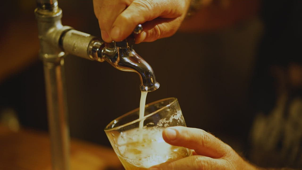 ⁣Bartender serving beer fro LIVE DRAW m a tap in a glass in the bar