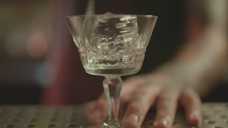 Bartender spinning an ice in a glass.