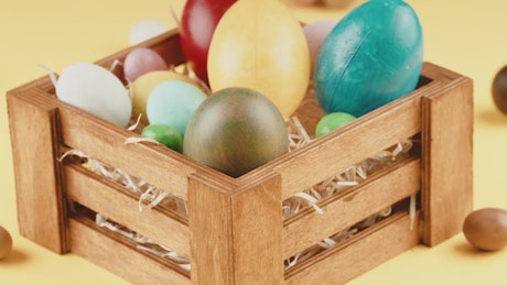 Basket of easter eggs rotating on a yellow background.