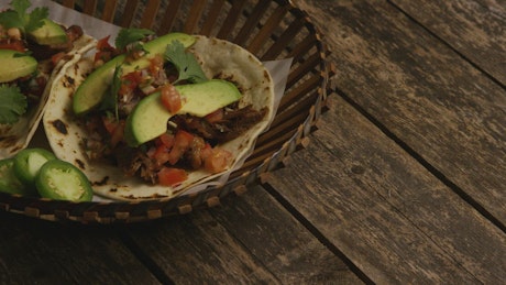 Basket of tacos with chicken and avocado.