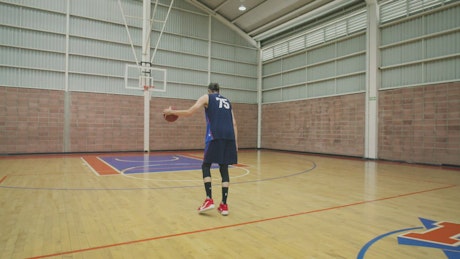 Basketball player dunking training a court alone.