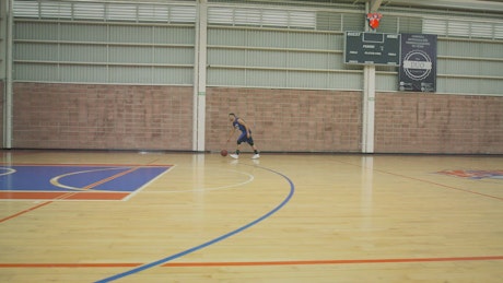 Basketball player shooting baskets while training alone.