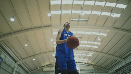 Basketball player training shots on a covered court.