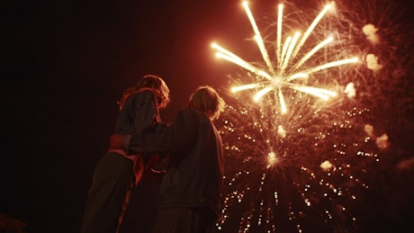 Beautiful fireworks display above a young couple in love.