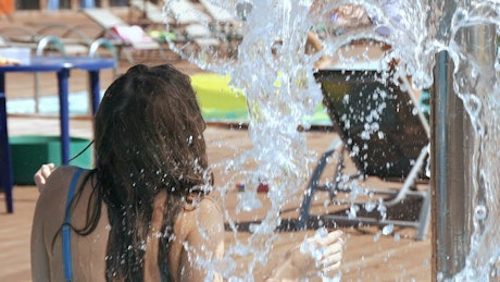 Beautiful girl in bikini splashed with water at resort.