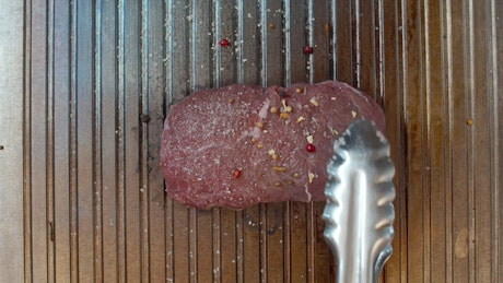 Beef tenderloin being seared on a grill.