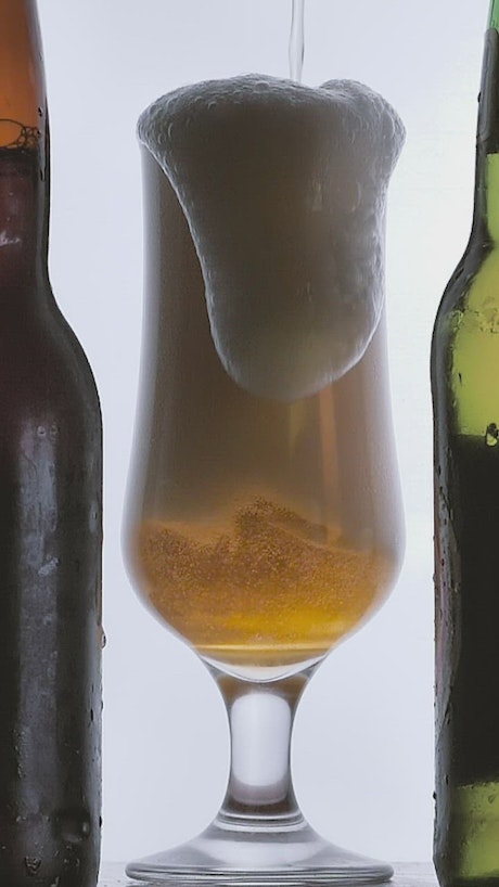 Beer foam spilling into a glass on white background.