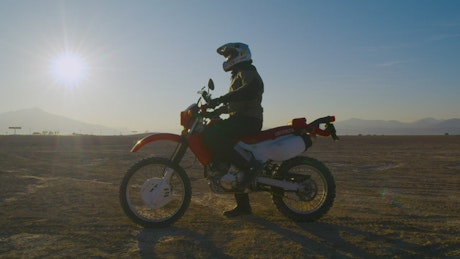 Biker starting his motorcycle in the desert.