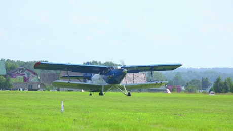 Biplane crossing the grass field.