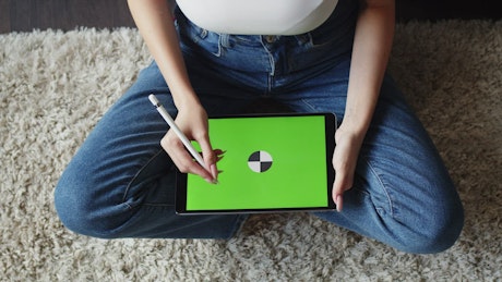 Birds eye view of a woman holding a tablet with a green screen.