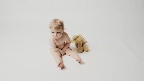 Blonde baby girl sitting in a white background